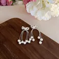Close-up view of elegant silver bowknot stud earrings with flowing pearl tassels - Silver Bow Style (White Pearl)