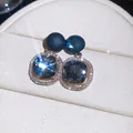 Macro view of geometric stud earrings featuring smoky grey crystals and sparkling halo - Black