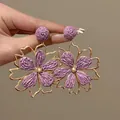 Dettaglio ravvicinato di orecchini a fiore in rafia viola con cornice dorata - Stile Fiore Vuoto (HE25316-4) / Oro Viola