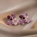 Primo piano di eleganti orecchini floreali viola con cristalli e perline su seta. - Stile Fiore in Cristallo con Strass / Oro Viola