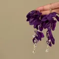 Dettaglio ravvicinato di eleganti orecchini a fiore in tessuto viola con nappe - Stile Nappa a Petalo in Tessuto / Oro Viola