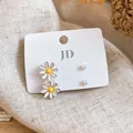 Detail view of dainty white daisy and pearl stud earring set on display card. - Daisy Pearl Set / Four-Piece Set / Silver White