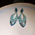 Close-up of bohemian hollow drop earrings with blue crystals and beads on silver needles. - Waterdrop Hollow Pendant Earrings / Blue