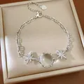 Close-up of an elegant silver-tone bracelet with star and round stone on a beige box. - Silver