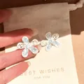 Close-up of elegant floral stud earrings with shimmering silver-tone flower petals. - Hollow Floral Stud Earrings (1#) / Silver-Blue