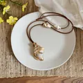 Detailed view of a Bohemian conch shell pendant necklace with a brown waxed cord. - Conch / Brown