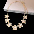 Dettaglio dei fiori in metallo dorato con perle su una cintura a catena vintage. - Oro-Bianco