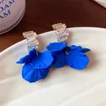 Primo piano di orecchini a petalo in acrilico blu Klein con zirconi scintillanti - Stile Petalo / Blu Klein-Oro