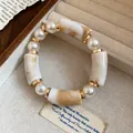 Detail view of a bohemian acrylic pearl bracelet with marble texture and gold accents - White-Coffee