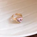 Close-up of exquisite heart-shaped pink gemstone on a textured gold-toned open ring for women - Heart Style / Pink