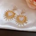 Gros plan de boucles d'oreilles cœur vintage dorées avec pendentifs soleil sur soie. - Heart Pendant (HE32553) / Blanc