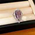 Detail of a luxury pear-shaped purple zircon ring with a sparkling halo in a jewelry box. - Water Drop Open Ring (HR3567) / Purple