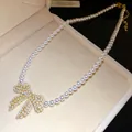 Nahaufnahme einer luxuriösen Perlenkette mit funkelndem Zirkonia-Schleifenanhänger - Schleife Perle Halsband Kette (HN11977) / Gold-Weiß