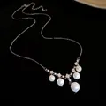 Détail d'un collier élégant avec perles et pendentifs en zircon sur surface noire brillante. - Style Pendentif Perle (HN11357) / Argent