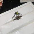 Close-up detail of a classic silver halo ring featuring a brilliant green round zircon - Open Adjustable Ring / Silver Ring - Green Zirconia
