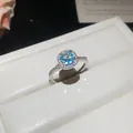 Macro view of a silver adjustable ring with a sparkling light blue round zircon stone. - Open Adjustable Ring / Silver Band-Blue Zirconia