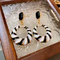 Detailed macro view of geometric earrings with black and white enamel spiral stripes - Hollow Geometric (HE16332-1) / Black & White Stripe