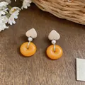 Detailed view of French vintage earrings featuring heart wood and orange resin rings - White/Yellow