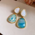 Close-up of vintage-style resin drop earrings with blue and white marble pattern - Blue