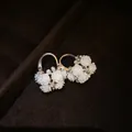 Close-up of French retro earrings with white resin flowers and rhinestones on velvet. - Rose Cluster Style