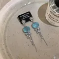 Dettaglio orecchini a rosa blu con nappe argentate su un vassoio elegante - Orecchini a Bottone con Nappa Rosa / Blu