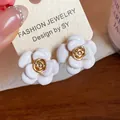 Gros plan sur des boucles d'oreilles camélia en émail blanc avec centre plaqué or 18 carats - Blanc (Plaqué Or 18K)