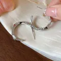 Close-up of minimalist silver-plated C-shaped hoop earrings with zircon stones. - Silver