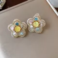 Detalle de cerca de los elegantes pendientes de flores de resina con perlas y circonitas. - Forma de Flor / Un par / Dorado