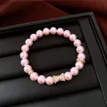 Primo piano di bracciale di perle rosa con fiocco in zircone su vassoio portagioie. - Rosa