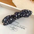 Close-up detail shot of black floral bow hair banana clip on a white jewelry display - Black & White Floral