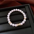 Dettaglio macro di bracciale di perle bianche con elemento a fiocco in zircone - Bianco