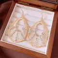 Close-up of elegant rhinestone hollow waterdrop dangle earrings in a wooden jewelry box - Pear Shape Pendant / Ear Hooks - Gold - White