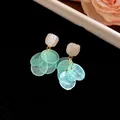 Detail shot of elegant cat eye stone earrings with mint green semi-transparent tassel discs - Blue