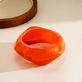 Close-up of a chunky orange resin geometric bangle with irregular fashion design - Orange