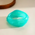 Close-up of a turquoise irregular geometric resin bangle with white marble texture - Cyan