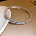 Detailed macro view of a silver-toned zircon bangle with inlaid blue and white stones - Silver-Blue