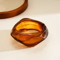 Detail showing the amber resin texture and irregular geometric shape of the hinged bangle. - Brown