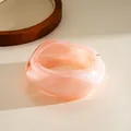 Detailed macro view of a translucent peach resin bangle with irregular geometric design - Pink
