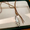 Dettaglio ravvicinato di un ciondolo a conchiglia metallica su collana in cuoio. - Stile Conchiglia (HN12518) / Argento-Caffè