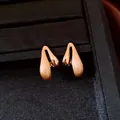 Detailed view of gold-plated teardrop earrings with elegant brushed finish. - Gold