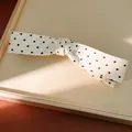 Detailed view of a white fabric hair clip with black polka dots and soft sunlight - Twist Clip / White
