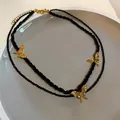 Detailed macro view of the retro layered black beaded necklace with golden butterfly pendants. - Gold-Black