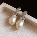Detail view of vintage silver stud earrings with large baroque pearl pendants on stone. - Silver (Silver Pin)