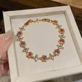 Detailed view of 18k gold plated bracelet with purple cubic zirconia flower charms - Flower Style (HB5804) / Gold-Pink