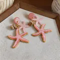 Primer plano de pendientes de estrella de mar de resina rosa con borde dorado - Forma de Estrella de Mar (HE33965) / Rosa