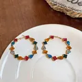 Detailed macro shot of colorful square and teardrop zircon hoop earrings on white plate. - Silver Earring Post - Colorful / Gold