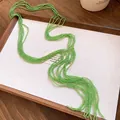 Detail of ethnic green crystal beaded multi-layer tassel necklace on a white display tray - Green
