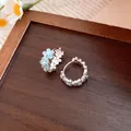 Close-up detail of silver hoop earrings featuring delicate light blue enamel flowers. - Ear Buckle / Blue