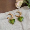 Detail of gold-plated C-hoop earrings with elegant green heart-shaped glass pendants. - 24K Gold Plated Heart (HE33034) / Gold-Green