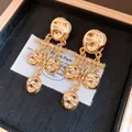 Detailed close-up of gold hammered metal dangle earrings with vintage wrinkled texture. - Pleated Pendant Style / Gold